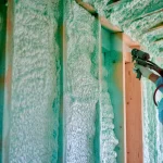 Une personne qui met de la mousse expansive dans les ossatures en bois d'une maison