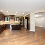 Quelle couleur choisir pour peindre une cuisine en bois foncé ? Une cuisine ouverte avec des placards en bois foncé et un parquet