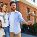 Un coule qui prend les clefs d'une maison avec une petite fille à côté