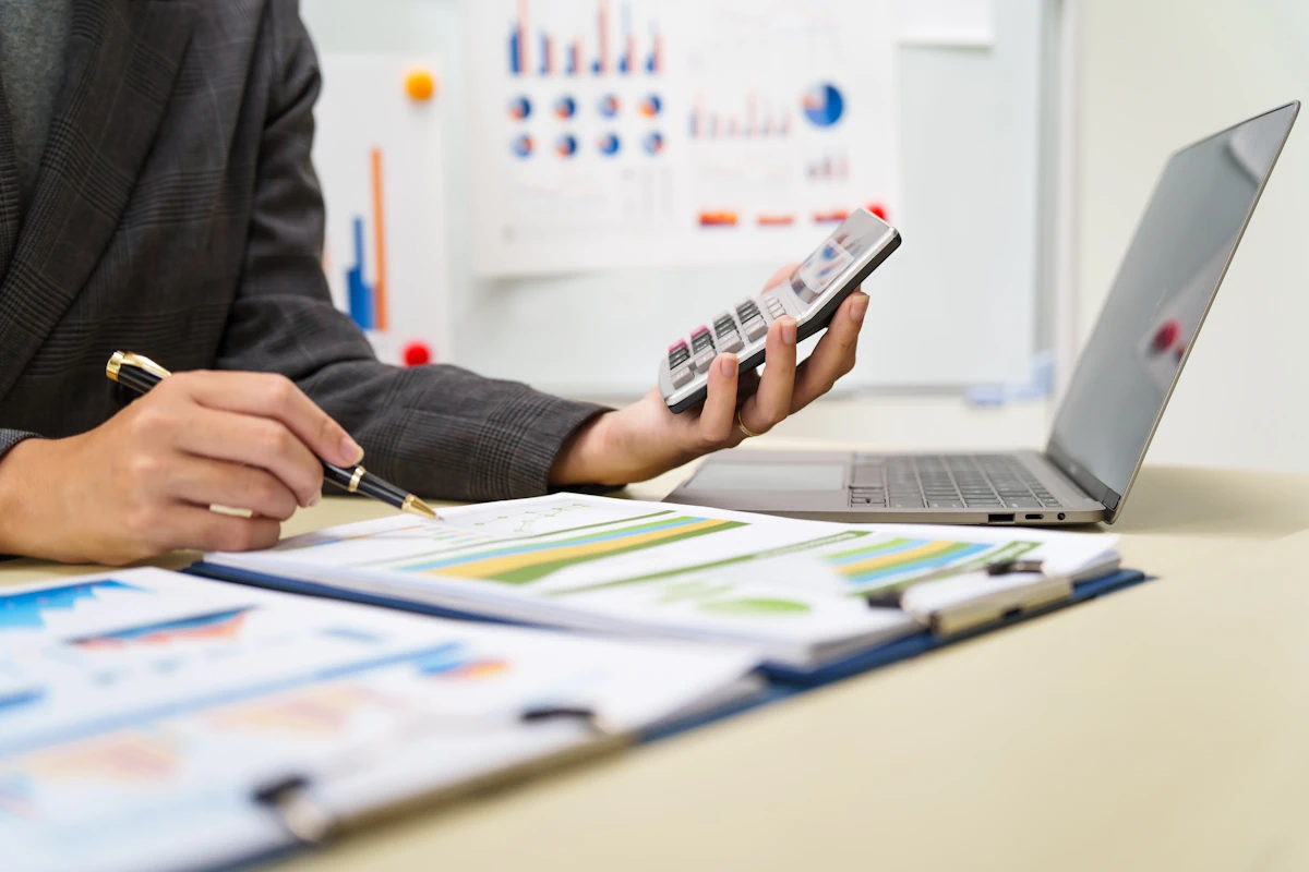 Une personne sur sa calculatrice en regardant des documents