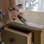 Une personne qui applique une patine sur un meuble en bois