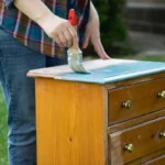Une personne qui peint un meuble en bois