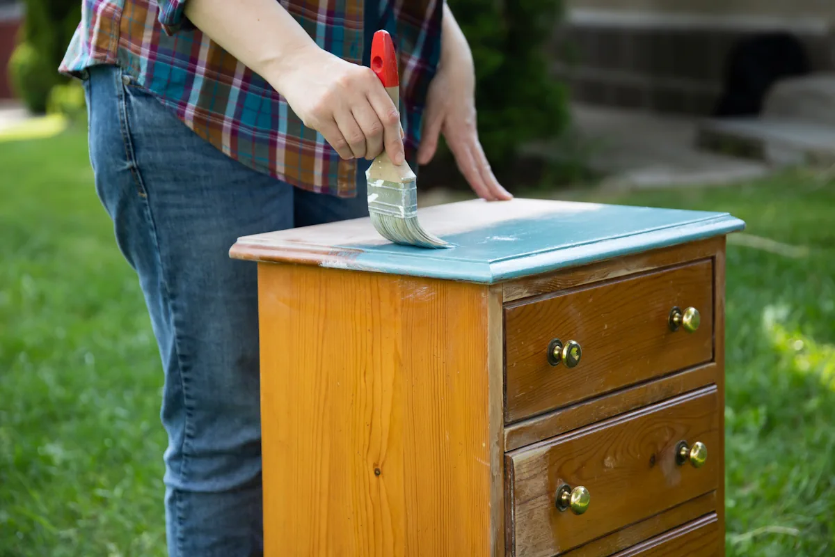 Une personne qui peint un meuble en bois