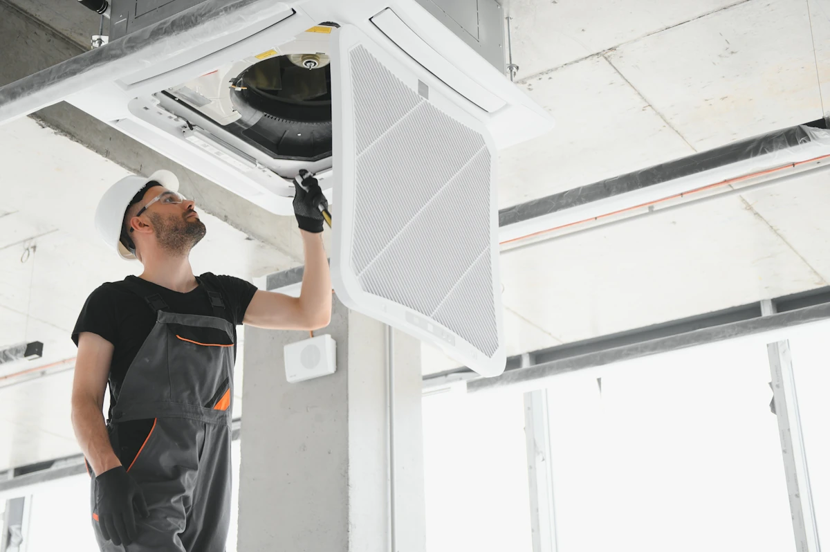 Un homme qui vérifie la bouche de ventilation d'un VMC simple flux